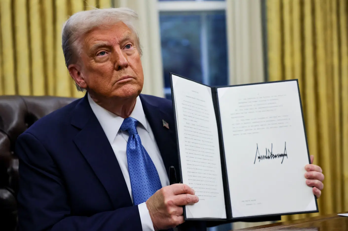 O presidente dos EUA, Donald Trump, segura uma ordem executiva no Salão Oval da Casa Branca, em Washington - 31/1/2025 | Foto: Carlos Barria/Reuters