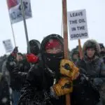 Um indígena norte-americano lidera uma marcha de protesto com veteranos e ativistas do lado de fora do acampamento Oceti Sakowin - 5/12/2016 | Stephen Yang/Reuters