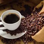 Grãos de café, ao lado da bebida pronta