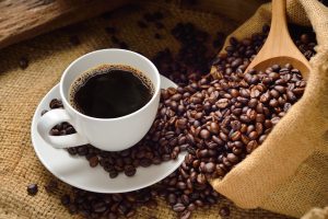 Grãos de café, ao lado da bebida pronta