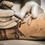 Profissional realiza procedimento de tatuagem em cliente