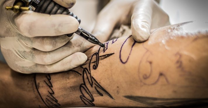 Profissional realiza procedimento de tatuagem em cliente