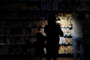 Pessoas usam celulares e lanternas para comprar mantimentos dentro de um supermercado, durante o apagão em Barcelona, Espanha - 28/5/2025 | Foto: Bruna Casas/Reuters