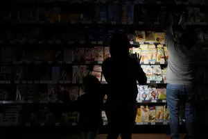 Pessoas usam celulares e lanternas para comprar mantimentos dentro de um supermercado, durante o apagão em Barcelona, Espanha - 28/5/2025 | Foto: Bruna Casas/Reuters