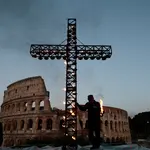 Um trabalhador acende uma cruz do lado de fora do Coliseu, antes da procissão da Via Crucis, durante as celebrações da Sexta-Feira Santa, em Roma - 18/4/2025 | Foto: Remo Casilli/Reuters