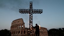 Um trabalhador acende uma cruz do lado de fora do Coliseu, antes da procissão da Via Crucis, durante as celebrações da Sexta-Feira Santa, em Roma - 18/4/2025 | Foto: Remo Casilli/Reuters