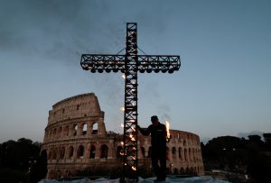 Um trabalhador acende uma cruz do lado de fora do Coliseu, antes da procissão da Via Crucis, durante as celebrações da Sexta-Feira Santa, em Roma - 18/4/2025 | Foto: Remo Casilli/Reuters