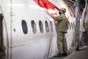 Funcionário aplica a película, inspirada na pele de tubarão, na fuselagem de um avião da companhia Austrian Airlines | Foto: Reprodução/Twitter/X
