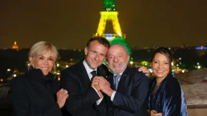 Lula e Janja posam ao lado de Emmanuel e Brigitte Macron, com a Torre Eiffel iluminada ao fundo nas cores da bandeira brasileira — símbolo do estreitamento de laços diplomáticos entre Brasil e França | Foto: Ricardo Stuckert/PR
