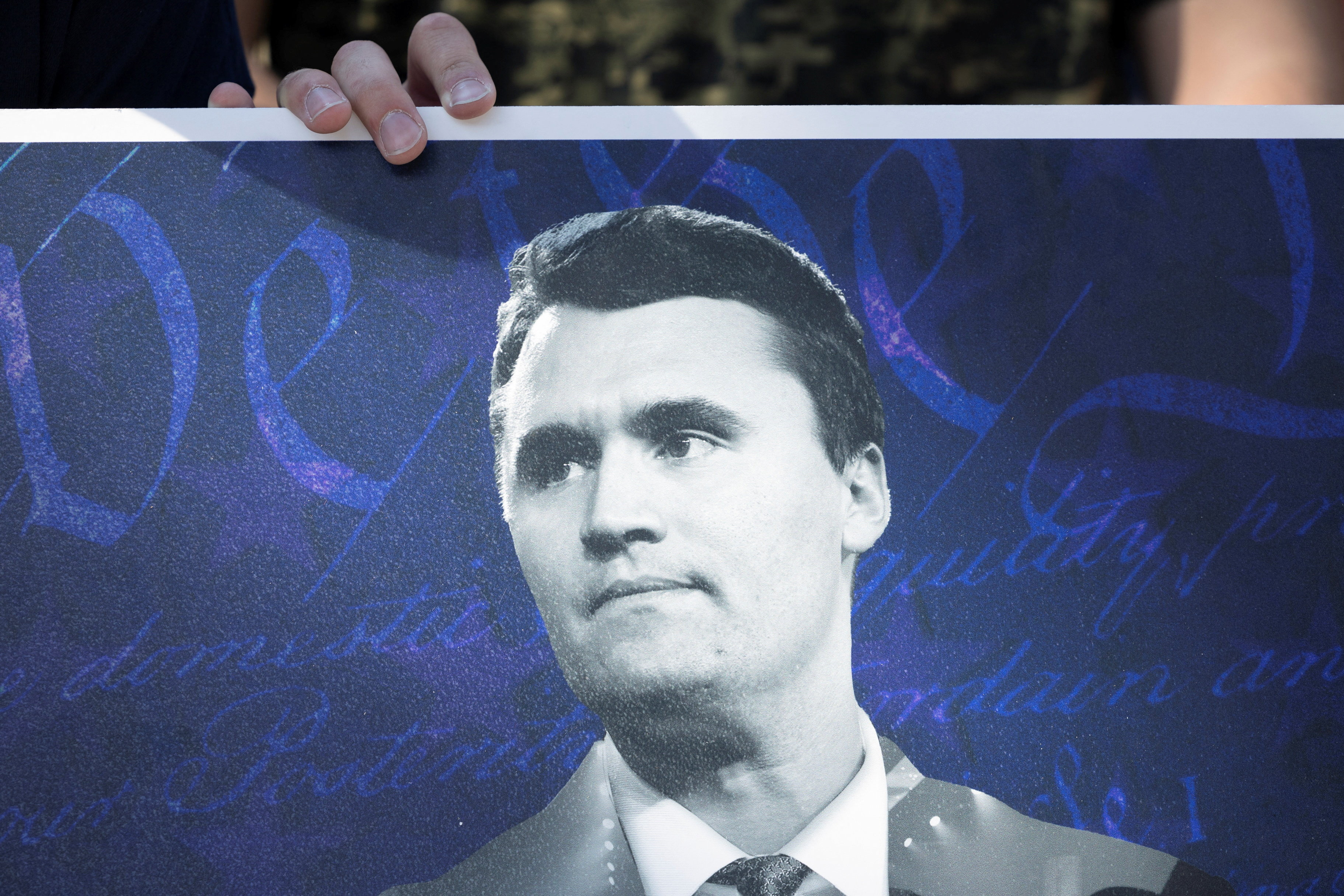 Um manifestante segura um cartaz do ativista conservador Charlie Kirk, em Houston, Texas - 11/10/2025 | Foto: Antranik Tavitian/Reuters