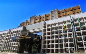 Fachada Tribunal de Justiça de Goiás; juíza ri em audiência de custódia