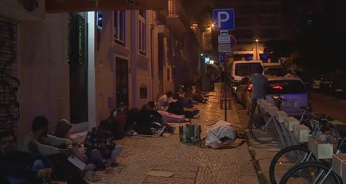Estrangeiros na calçada durante a madrugada em Lisboa: críticas à burocracia | Foto: Reprodução/Twitter/X
