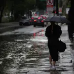 Pedestres enfrentam chuva forte, em alusão à nota sobre alerta vermelho do Inmet