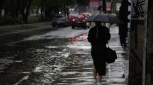 Pedestres enfrentam chuva forte, em alusão à nota sobre alerta vermelho do Inmet