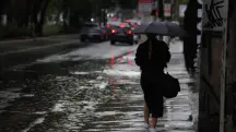 Pedestres enfrentam chuva forte, em alusão à nota sobre alerta vermelho do Inmet