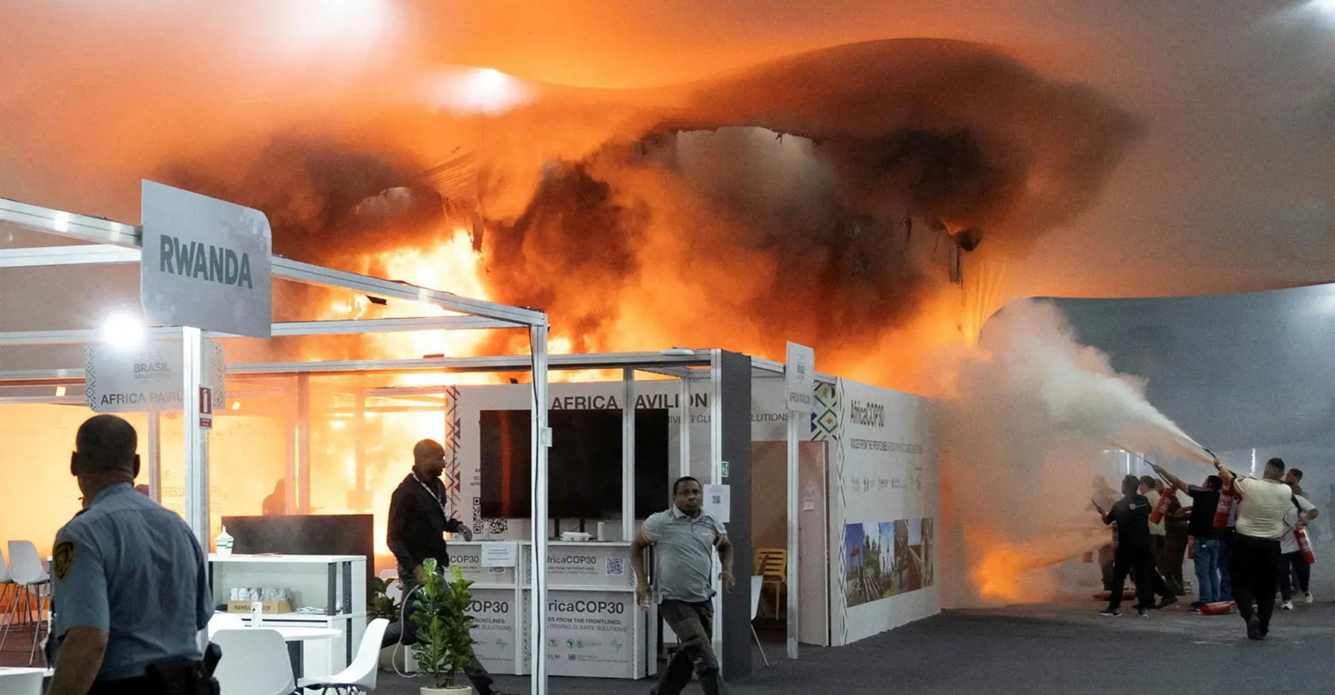Pessoas usam extintores de incêndio para apagar fogo no Pavilhão dos Países da Zona Azul na Conferência das Nações Unidas sobre Mudanças Climáticas (COP30) em Belém, Brasil (20/11/2025)