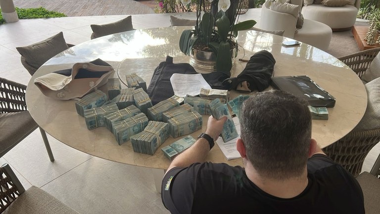 Agente da PF conta parte dos R$ 1,6 milhão apreendidos em casa de envolvidos em suposta fraude financeira | Foto: Divulgação/PF