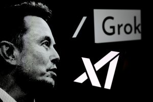logotipo da Grok é exibido em um smartphone com Elon Musk ao fundo | Foto: Shutterstock
