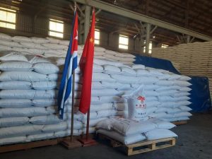 Bandeiras da China e de Cuba; ao fundo, sacos de arroz enviados pelo país asiático à ilha