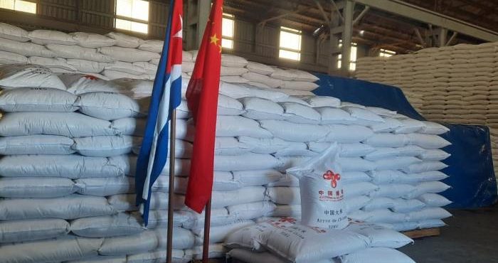 Bandeiras da China e de Cuba; ao fundo, sacos de arroz enviados pelo país asiático à ilha
