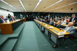 Audiência legislativa com parlamentares sentados em plenário durante discussão orçamentária em comissão