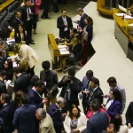 Parlamentares, assessores e jornalistas reunidos no plenário do Congresso Nacional durante sessão, com registros e articulações políticas.