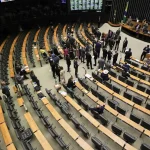 Câmara - Vista superior do plenário da Câmara dos Deputados com parlamentares reunidos durante sessão legislativa no Congresso Nacional.