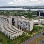 Vista aérea da sede do Superior Tribunal de Justiça em Brasília, com prédios modernos, áreas verdes e lago ao fundo.