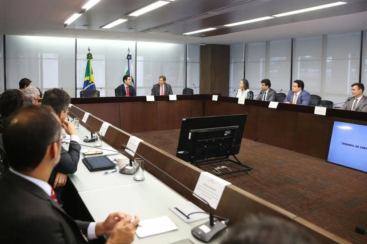 Reunião institucional em plenário de tribunal com autoridades sentadas em mesa semicircular durante sessão oficial