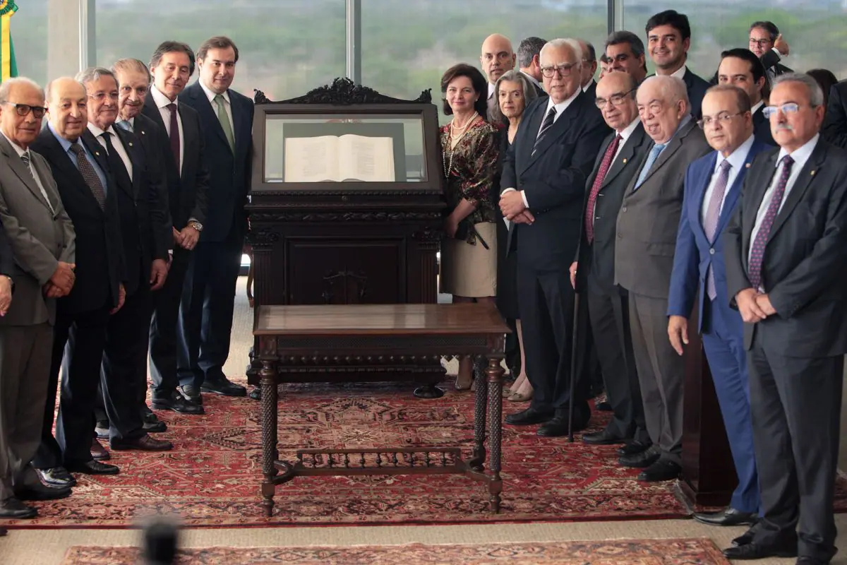 Autoridades dos Três Poderes reunidas em cerimônia solene no Supremo Tribunal Federal, ao redor de exemplar da Constituição Federal exposto.