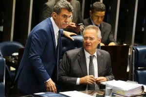 Parlamentares conversam durante sessão legislativa com documentos sobre gastos públicos sobre a mesa