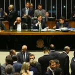 Parlamentares reunidos no plenário da Câmara dos Deputados durante sessão deliberativa, com mesa diretora e deputados em debate.