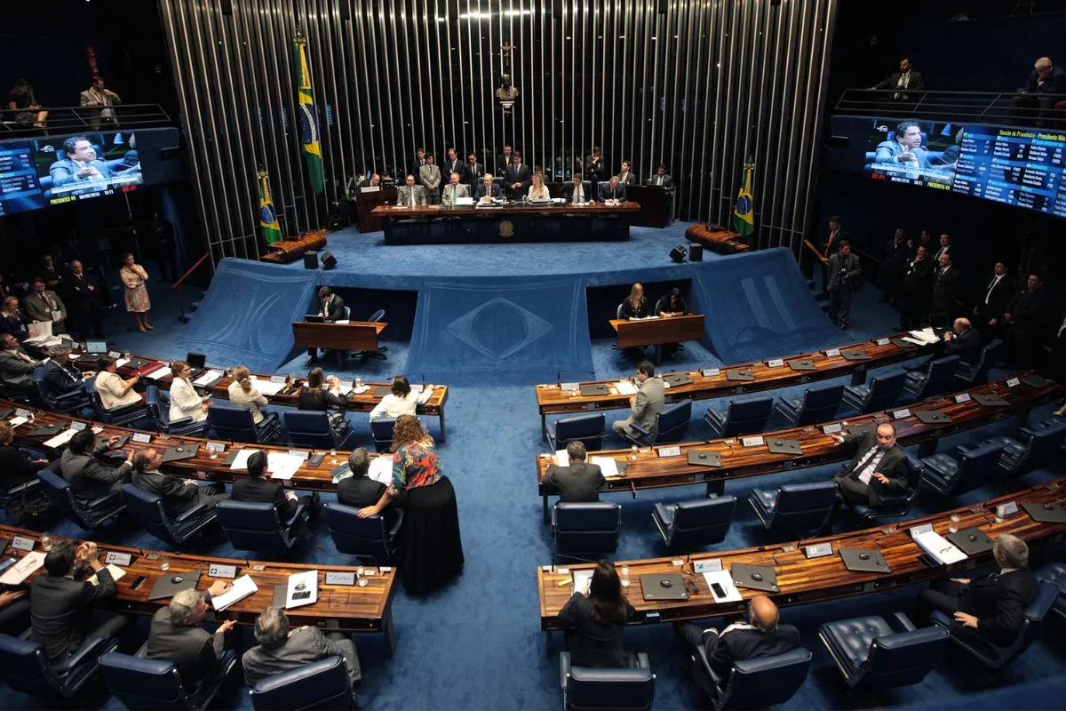 Vista ampla do plenário do Senado Federal durante sessão legislativa, com senadores, mesa diretora e painéis eletrônicos.