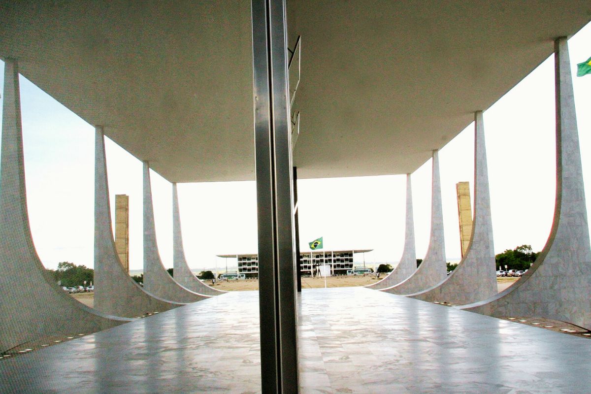 Vista interna do Supremo Tribunal Federal em Brasília, com colunas curvas e a Praça dos Três Poderes ao fundo