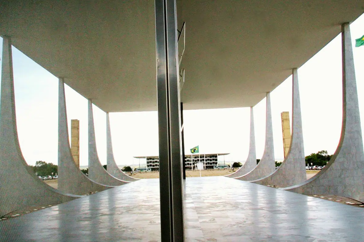 Vista interna do Supremo Tribunal Federal em Brasília, com colunas curvas e a Praça dos Três Poderes ao fundo