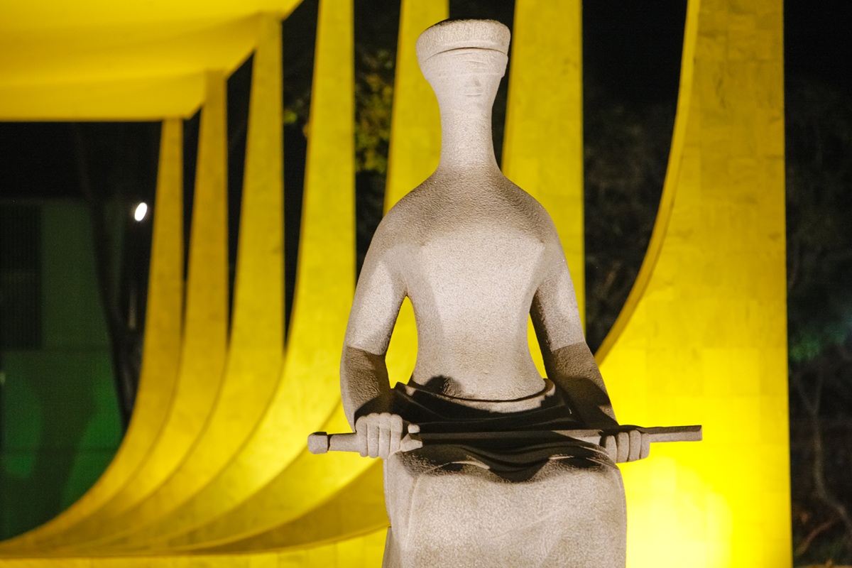 Estátua da Justiça segurando espada em frente ao prédio do Supremo Tribunal Federal, representando julgamento, constitucionalidade e projetos de lei.
