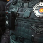 Colete tático da Polícia Militar de São Paulo com câmera corporal acoplada e distintivos oficiais da corporação