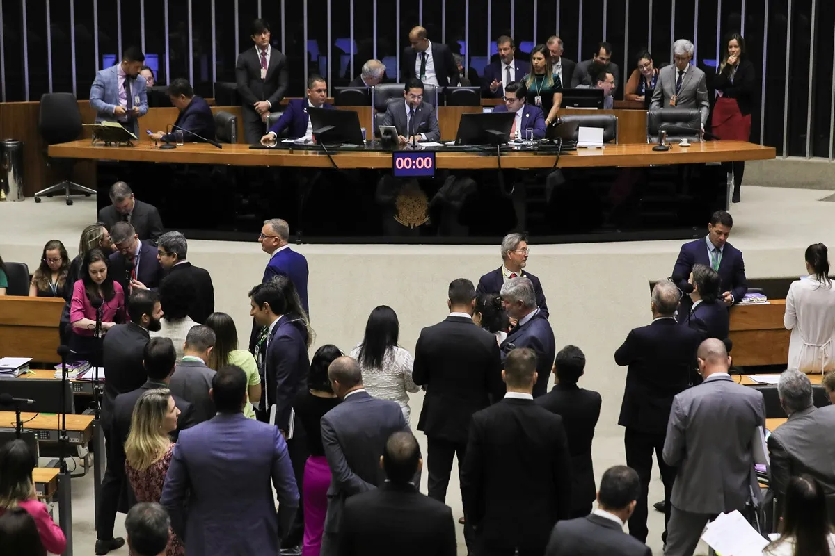 Parlamentares reunidos no plenário do Congresso Nacional durante sessão, com mesa diretora ao fundo e deputados em articulação.