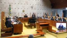 Plenário do Supremo Tribunal Federal com ministros togados durante sessão de julgamento, bandeira do Brasil e crucifixo ao fundo.