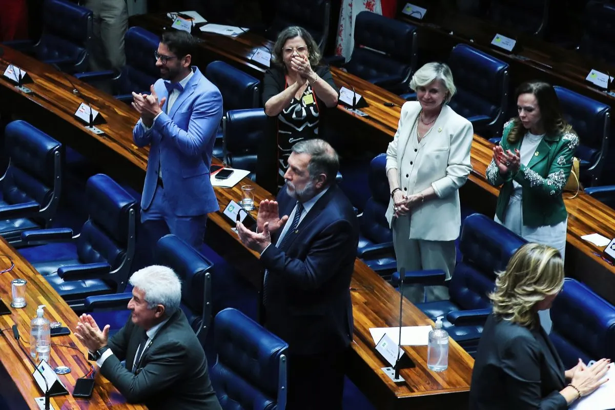 Parlamentares em pé aplaudindo durante sessão no plenário do Congresso Nacional, após votação ou decisão legislativa