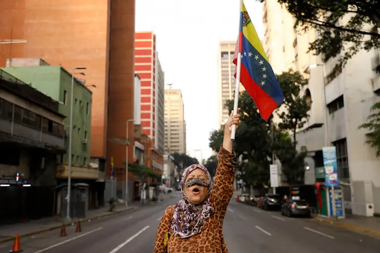 Manifestante ergue bandeira da Venezuela, país que se vê livre do ditador Nicolás Maduro
