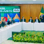 Reunião do governo Lula com autoridades e ministros, bandeiras do Brasil ao fundo e painel “Brasil Mais Justo”