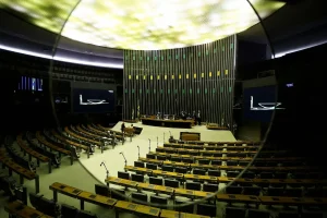 Plenário legislativo amplo com bancadas vazias e mesa diretora preparada para sessão oficial