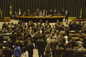 Plenário da Câmara dos Deputados lotado durante sessão legislativa, com parlamentares reunidos no salão e mesa diretora ao fundo.
