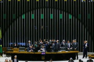 Mesa diretora em plenário legislativo com parlamentares reunidos durante momento decisivo da sessão