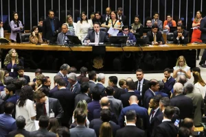 Sessão de votação em plenário com autoridades na mesa diretora e grande concentração de parlamentares no ambiente