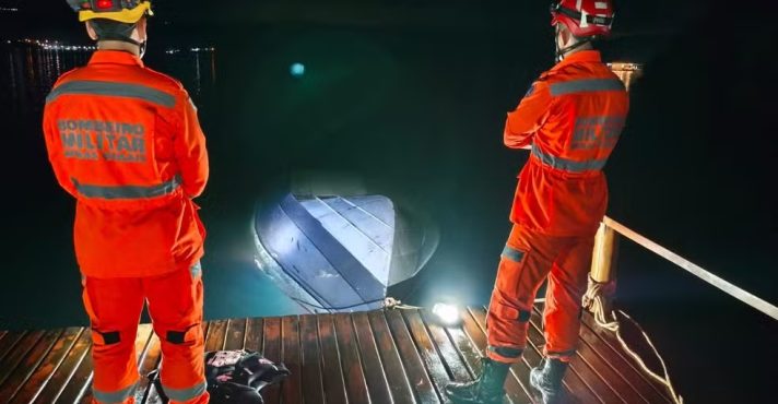 Bombeiros observam casco de embarcação que se chocou com píer na noite deste sábado, no interior de Minas Gerais | Foto: Divulgação/Corpo de Bombeiros