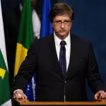 Autoridade brasileira discursando em tribuna durante pronunciamento oficial, com bandeiras ao fundo.