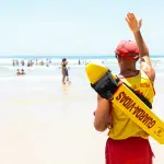 Bombeiro acena para banhista em praia do litoral de São Paulo | Foto: Divulgação/Agência SP