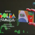 Cartão do Novo Bolsa Família exibido em tela com mensagem sobre cuidado e transformação social